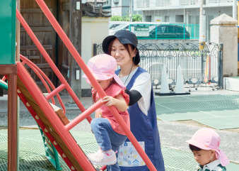 遊具で遊ぶ子どもを見守る先生